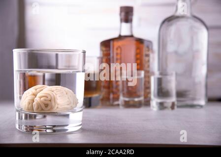 cerveau humain dans un verre avec une boisson alcoolisée, sur fond de bouteilles avec de l'alcool. Dépendance à l'alcool. Dommage au cerveau de l'alcool Banque D'Images