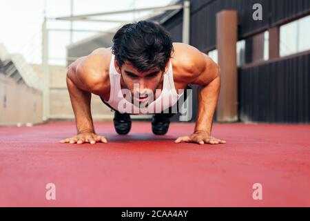 beau sportif qui fait des push-up sur un plancher rouge, concept de sport urbain et de mode de vie sain, copier l'espace pour le texte Banque D'Images