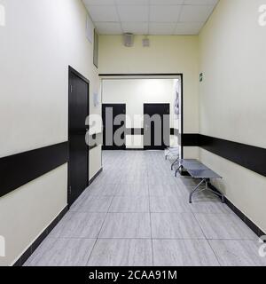 couloir vide dans le bâtiment moderne. Il y a de nombreuses portes brunes le long d'un très long couloir avec des murs beige. Banque D'Images