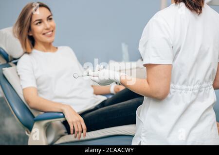 la jeune femme caucasienne s'assoit litlen aux recommandations du médecin avant le traitement des dents, souriant la femme caucasienne dans la chambre du dentiste Banque D'Images