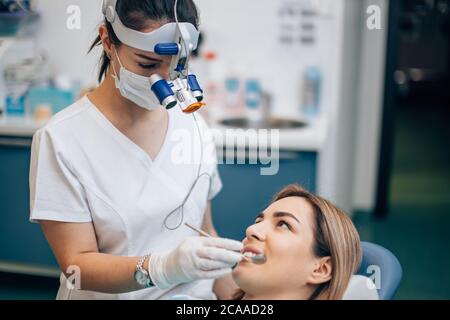 femme dentiste soigneuse en uniforme de médecin blanc traitant les dents, orthodontiste professionnelle utilisant des instruments médicaux spéciaux Banque D'Images