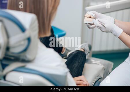 le dentiste et le patient non reconnaissables sont cultivés dans un cabinet dentaire, le médecin présente une prothèse au patient. Concept de santé et de médecine Banque D'Images