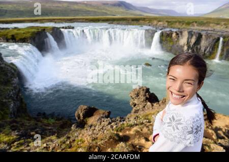 Portrait de femme en voyage par la cascade Godafoss sur l'Islande. Bonne jeune femme touristes appréciant paysage de la nature islandaise visite de touristes célèbres Banque D'Images