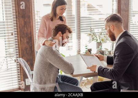 Caucasiens respectable couple achetant appartement, acheteurs de biens immobiliers prêts à conclure un contrat avec agent immobilier après signature de documents pour le Royaume Banque D'Images