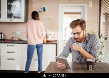 Portrait of caucasian businessman intelligent agréable la lecture des nouvelles sur smartphone, boire du café et de parler à la légère femme habillée. Banque D'Images