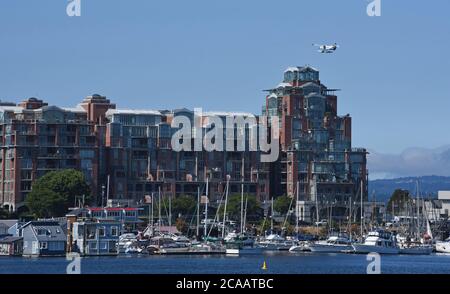 Victoria (Colombie-Britannique), Canada, 05 AOÛT 2020 - UN hydravion de passagers commerciaux de Harbour Air flotte au-dessus de l'immeuble de condominiums Shoal point et des bateaux à quai et des bateaux à quai à quai Fisherman's Wharf après avoir pris le bateau du port. Les compagnies aériennes de floatplane desservent à la fois les marchés locaux des transports de banlieue et les marchés touristiques. Don Denton/Alamy Live News Banque D'Images