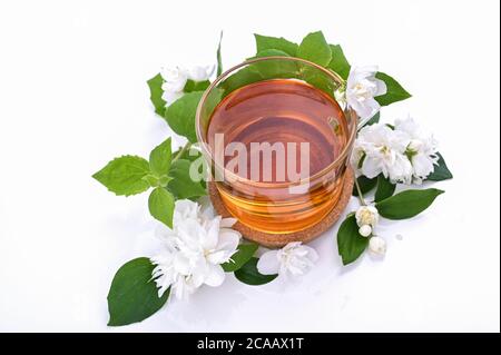 Thé au jasmin. Une boisson traditionnelle en Chine pour la santé et la vitalité. Médecine orientale. Fleurs de jasmin fraîches sur fond blanc et une tasse de thé. Espace libre pour le texte. Photos de couleurs claires Banque D'Images