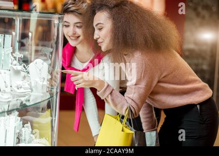 Deux amis féminins tendance à la recherche shopping à la boutique de bijoux dans le grand magasin d'achat et de choisir pour les bijoux parfaits à la fête de nuit Banque D'Images