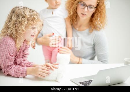 jeune fille aux cheveux bouclés regardant un dessin animé alors que sa mère s'occupe d'un bébé. gros plan photo rognée Banque D'Images