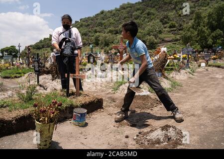 Chalco, Mexique. 05th Aug, 2020. Un jeune garçon de 10 ans travaille à mélanger le ciment pour les pierres tombales. La femme tient la pierre tombale de sa tante. Son oncle est enterré à quelques mètres. Ils sont tous deux morts de covid, dans une semaine l'un de l'autre. Depuis le 1er mai, une nouvelle zone du cimetière a été ouverte pour faire place à des centaines de décès dus au coronavirus. Les creuseurs de tombes creusent généralement 2 ou 3 tombes par semaine mais jusqu'à récemment, ils creusaient 2 ou 3 tombes par jour. Environ 500 nouvelles tombes ont été creusées depuis le début du mois de mai. Credit: Lexie Harrison-Cripps/Alamy Live News Banque D'Images