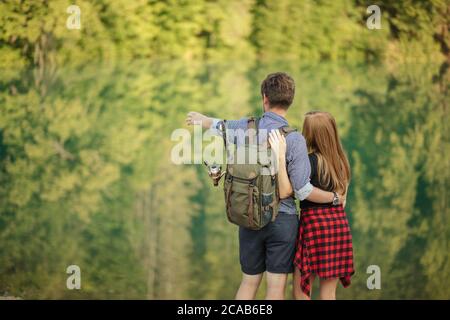 un jeune homme amoreux est debout avec sa petite amie et pointe vers la nature magnifique. vue arrière photo.vacances, concept de jour de congé. espace de copie Banque D'Images