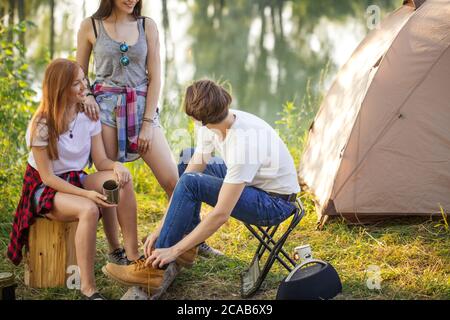 un jeune voyageur qui met des chaussures en place pendant que ses amis le regardent. gros plan sur une photo courte. concentrez-vous sur l'homme Banque D'Images