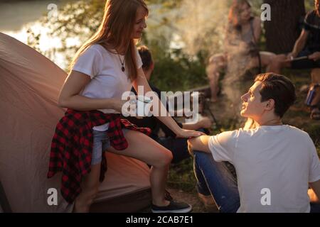 ginger awesome fille flirte avec fai-cheveux beau garçon au camping. belle femme avec une tasse tenant le bras de l'homme. gros plan photo. love concept Banque D'Images