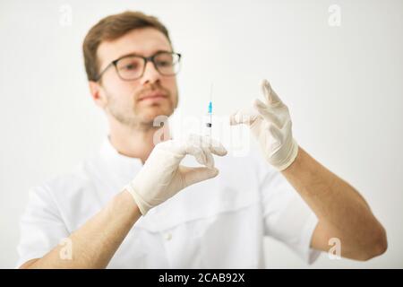 Soins de santé en clinique. Jeune ouvrier médical tenant une seringue. Photo rapprochée. Fond blanc isolé Banque D'Images