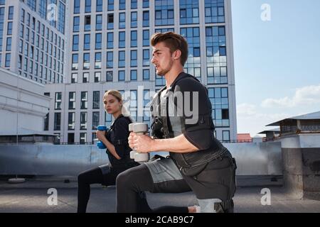 entraîneur personnel masculin est en train de faire de l'exercice avec un client féminin. préparation pour la compétition. vue latérale photo rognée Banque D'Images