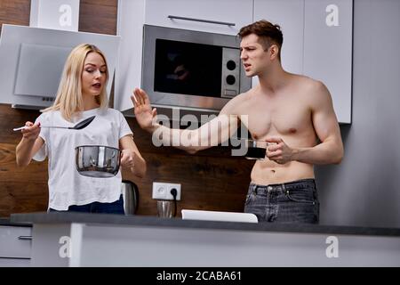 homme insatisfait de ce que sa femme cuisine le matin, l'homme et la femme en colère arguent, allant divorcer Banque D'Images