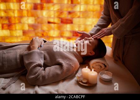 Belle dame portant un peignoir allongé sur le bureau pour les massages, profitez d'un massage du visage dans le salon de spa. Santé et traitement du corps, concept de beauté Banque D'Images