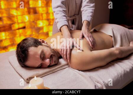 loisirs, repos, détente et massage. Beau homme aime recevoir un massage spa sur son dos fait par les mains des femmes. Banque D'Images