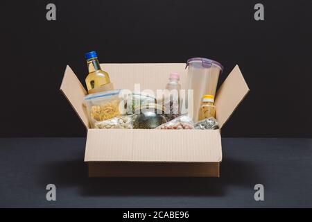 Donation box avec divers aliments. Ouvrir boîte en carton avec de l'huile, de la nourriture en conserve, céréales et pâtes alimentaires. Banque D'Images