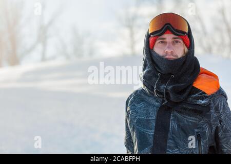 Jeune homme beau portant un masque de ski et une veste de sport qui se hante à l'appareil photo. Portrait en gros plan. Espace de copie. Style de vie, passe-temps Banque D'Images