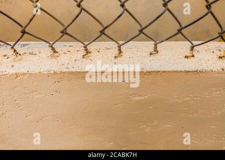 Gros plan de l'ancienne clôture en fil de fer filet d'époque sur le fond d'un mur peint en béton beige. Espace de copie idéal pour une utilisation dans le design ou le papier peint Banque D'Images