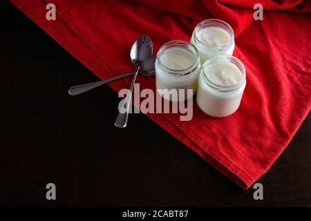 Yaourts en pots de verre sur un textile rouge Banque D'Images