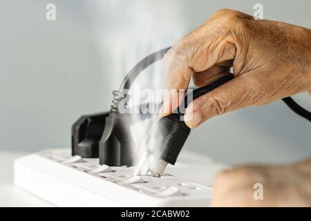 Main âgée avec étincelle de prise électrique Banque D'Images