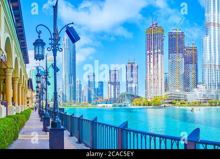 DUBAÏ, Émirats Arabes Unis - 3 MARS 2020 : l'étroite promenade du lac Burj à Al Bahar Souq (marché) est une allée populaire pour les promenades de loisirs et un point de vue sur le Surrou Banque D'Images
