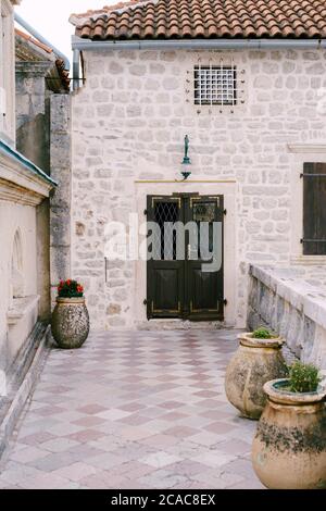 L'entrée de la maison est fermée porte en métal avec une grille à travers la cour avec de grands pots pour fleurs. Banque D'Images