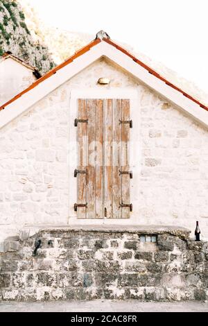 Ancienne porte en bois au grenier dans un mur blanc avec un toit orange. Banque D'Images