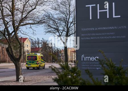 Helsinki, Finlande - 4 avril 2020: Signe extérieur de l'Institut national finlandais de la santé et du bien-être social (THL) avec une ambulance passant sur Mannerh Banque D'Images