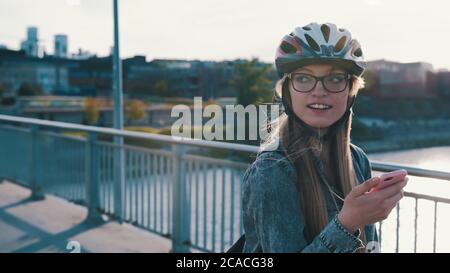 Portrait d'une jeune femme heureuse patinant sur le pont et utilisant un smartphone. . Photo de haute qualité Banque D'Images