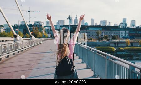 Jeune femme avec sac à dos. Concept de liberté. Lever les mains dans l'air. Plan de suivi du piédestal. Photo de haute qualité Banque D'Images