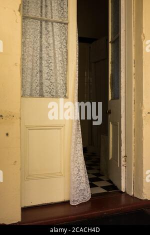 Rideau soufflant dans une porte ouverte à une chambre dans une maison de style Queenslander ancienne avec portes-fenêtres Banque D'Images