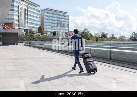 Vue arrière de Young businessman Walking dehors avec bagages Banque D'Images