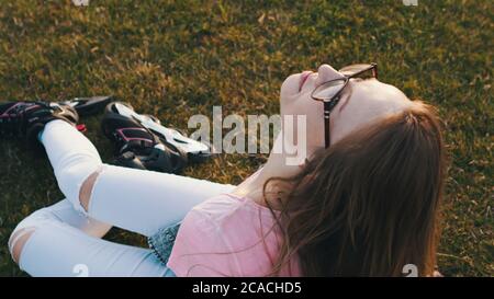 Une adolescente avec des rollers sur ses pieds se reposant sur la prairie. Liberté et rêve de jour. Photo de haute qualité Banque D'Images