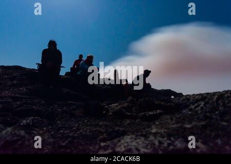 Silhouettes de personnes assises au bord du cratère du volcan Erta Ale, en Éthiopie, en pleine lune Banque D'Images