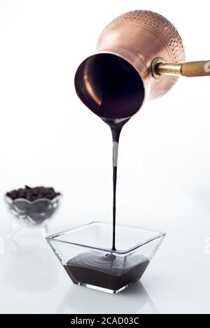 Une dose verticale de sirop de chocolat est versée un pot de glace sur un bol en verre Banque D'Images