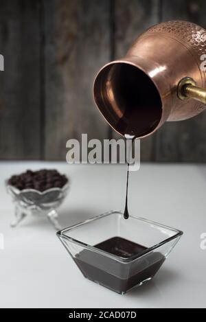 Une dose verticale de sirop de chocolat est versée un pot de glace dans un bol en verre Banque D'Images