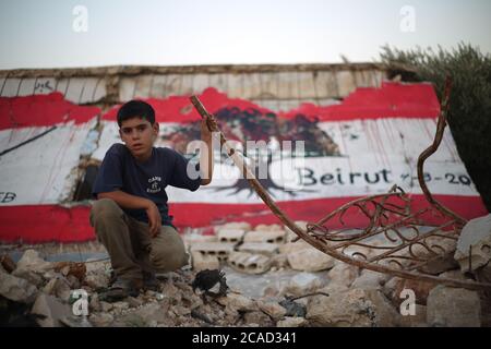 Idlib, Syrie. 05 août 2020. Un enfant syrien pose devant une fresque un drapeau libanais sur les murs de la ville de Bennach, à l'est d'Idlib, le 6 août 2020, pour la solidarité des Syriens avec le peuple libanais après l'exposition du port de Beyrouth à une énorme explosion hier, tuant plus de 100 et 4000 blessés. (Photo par Ali Haj Suleiman/INA photo Agency/Sipa USA) crédit: SIPA USA/Alay Live News Banque D'Images