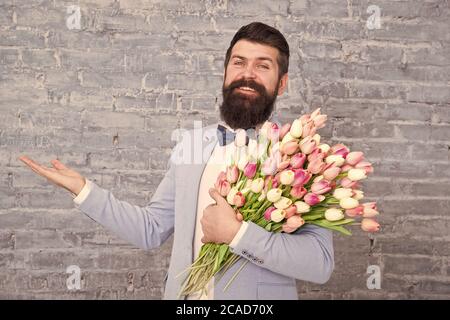 Choses qui font l'homme gentleman. Homme romantique avec des fleurs. Cadeau romantique. Macho prêt date romantique. Tulipes pour elle. L'homme grand Bow-tie tuxedo tenir fleurs bouquet. De cœur sincère. Banque D'Images