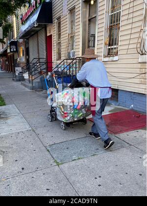 L'homme travaille dur à la collecte de boîtes en aluminium jetées pour gratter une vie le long d'une rue à Brooklyn, New York. Banque D'Images