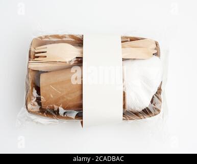 assiettes et tasses en papier en papier brun artisanal et fourchettes et couteaux en bois isolés sur fond blanc. Concept de rejet plastique, zéro déchet, kit Banque D'Images