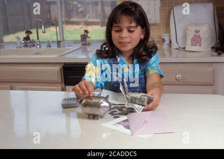 Austin Texas États-Unis, 1998 : huit ans, une jeune fille panaméenne-américaine prépare le dépôt pour le compte d'épargne à partir de dollars et de pièces qu'elle a économisé.. MR ©Bob Da Banque D'Images