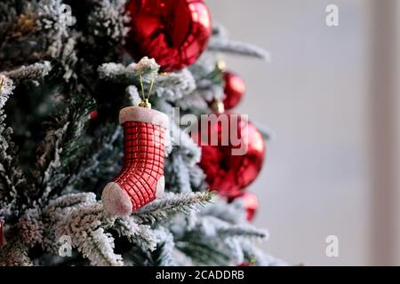 Chaussette de gros plan et boules rouges sur l'arbre de noël. Flou d'arrière-plan de mur blanc Banque D'Images