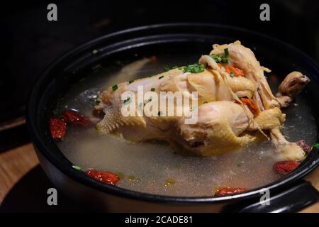 Gros plan sur la soupe de poulet au ginseng dans un pot noir. Cuisine traditionnelle en Chine et en Corée. Arrière-plan sombre flou Banque D'Images