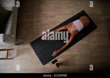 Vue en grand angle d'une jeune femme assise sur un tapis de yoga qui fait de l'exercice d'étirement Banque D'Images