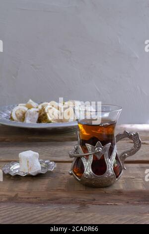 Thé turc dans une tasse de verre traditionnelle sur une table en bois. Des sucreries orientales et une boisson chaude. Copier l'espace. Banque D'Images