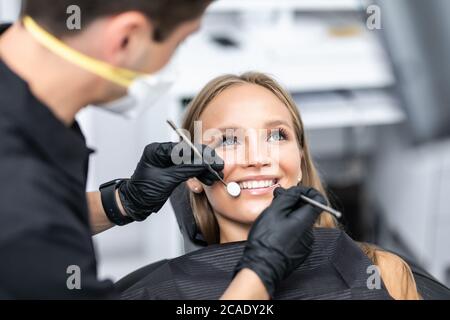 La femme est venue pour voir le dentiste. Elle s'assoit sur le fauteuil dentaire. Le dentiste se pencha sur elle. Heureux patient et dentiste concept. Banque D'Images