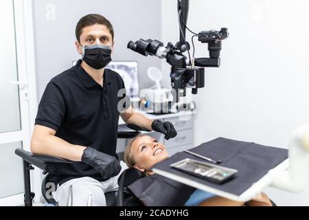 Dentiste homme travaillant dans une clinique privée de dentisterie avec de l'équipement moderne, microscope professionnel. Banque D'Images
